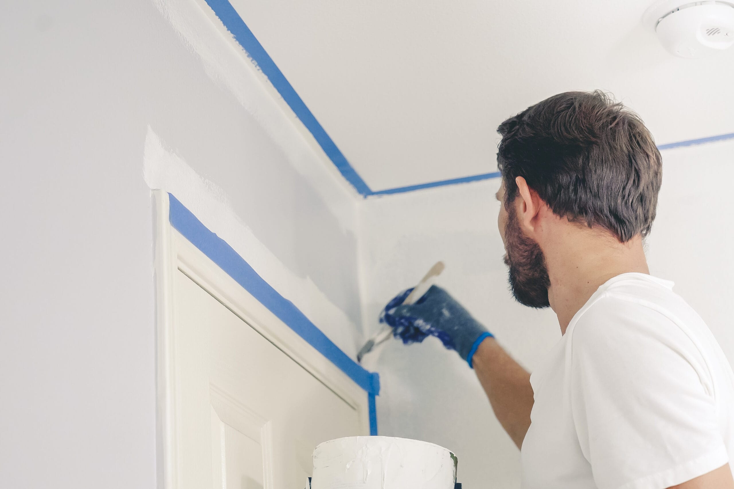 Close up of painter hands with gloves painting the wall edge by